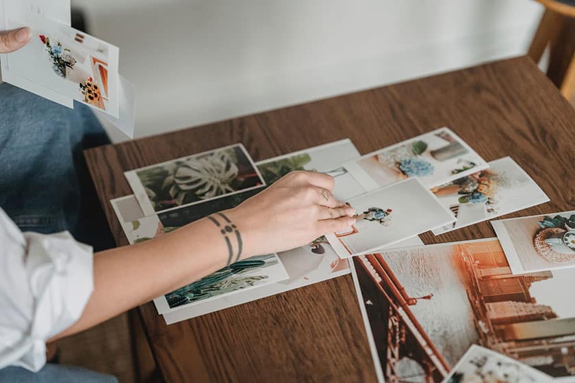 person looking at photographic prints on table